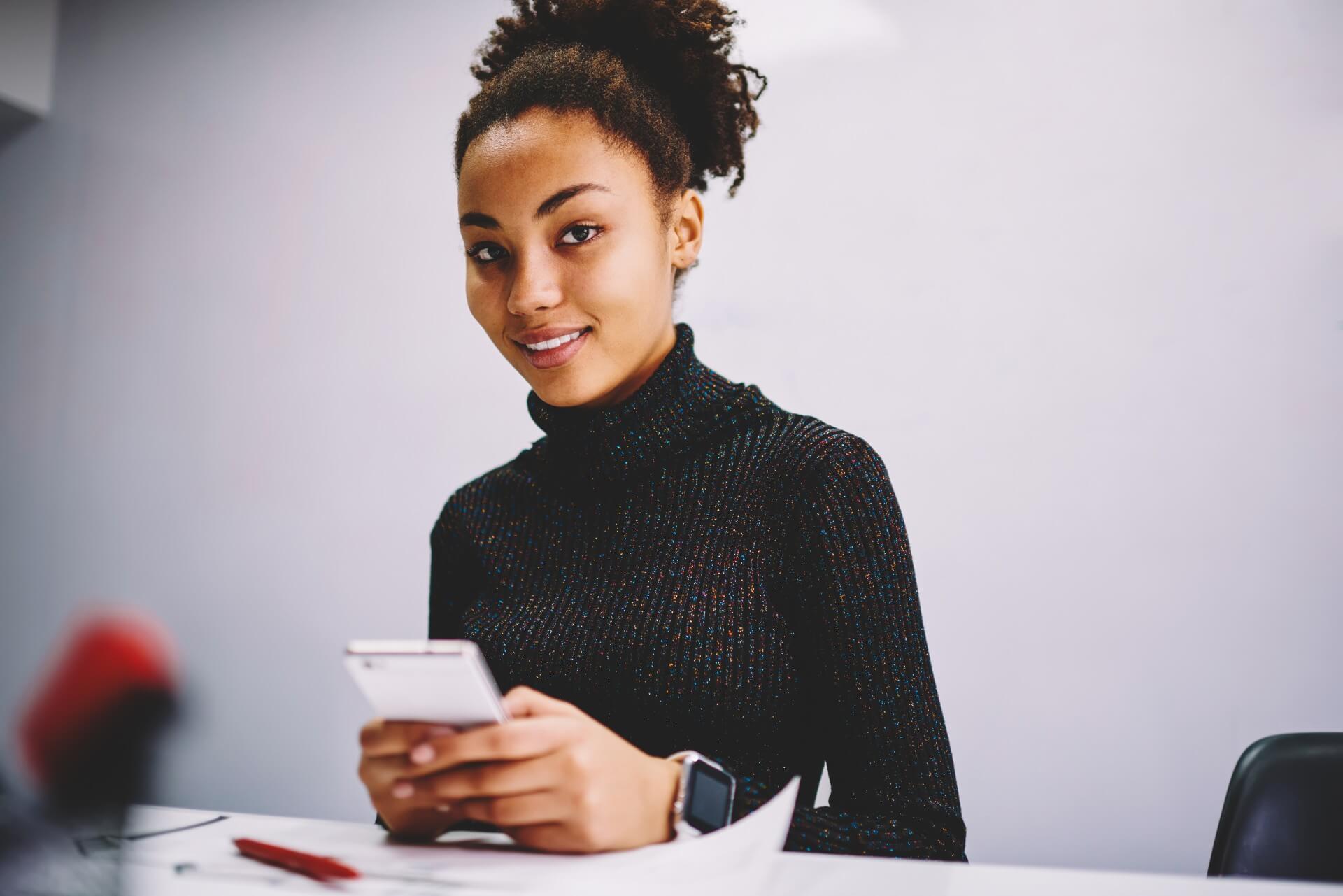 Young dark-skinned female student using a cell phone