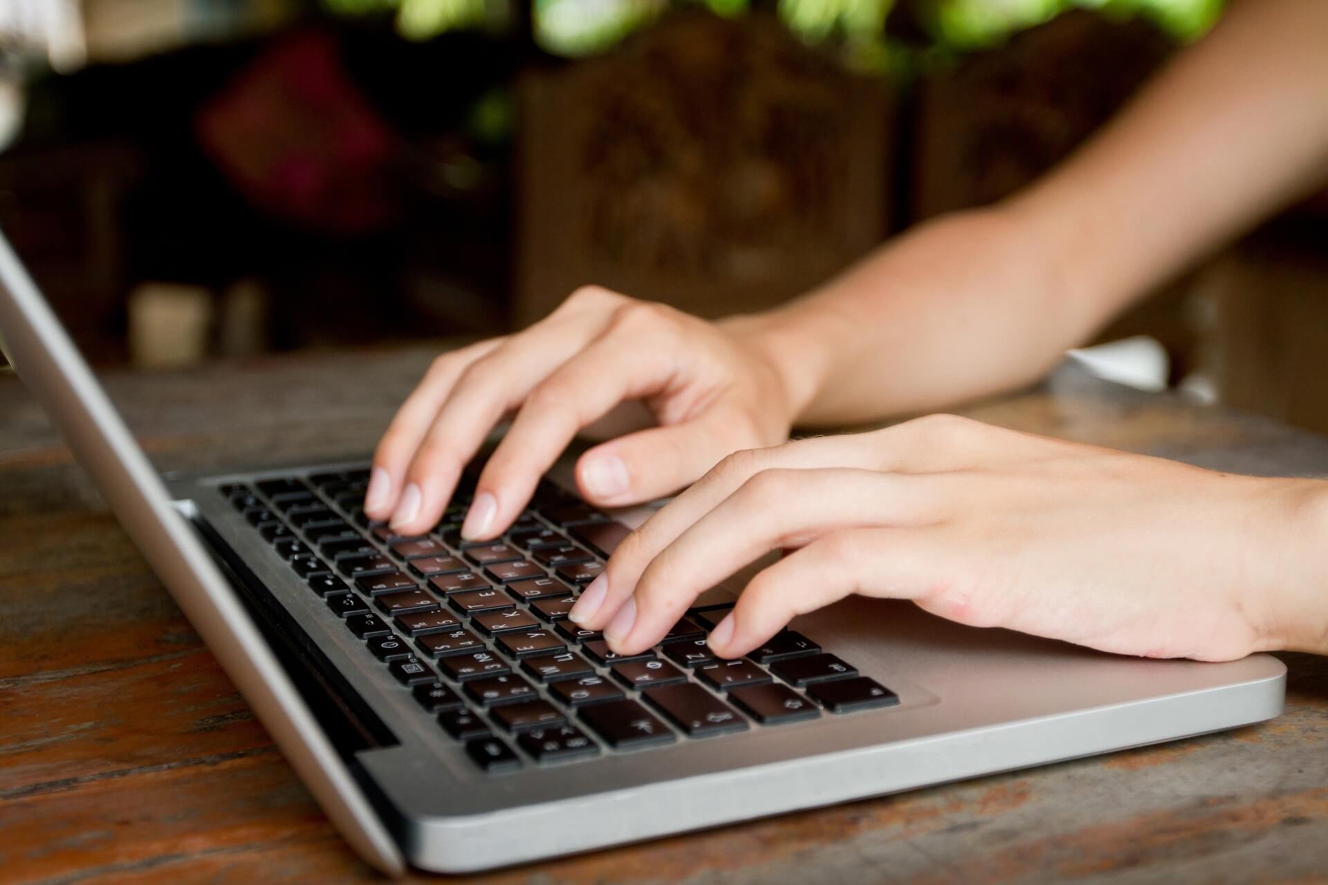 Hands writing on a laptop keyboard