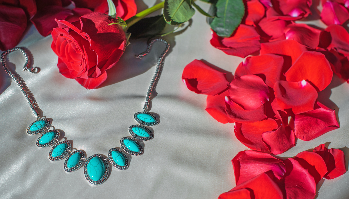 Blue stone necklace surrounded by rose pedals