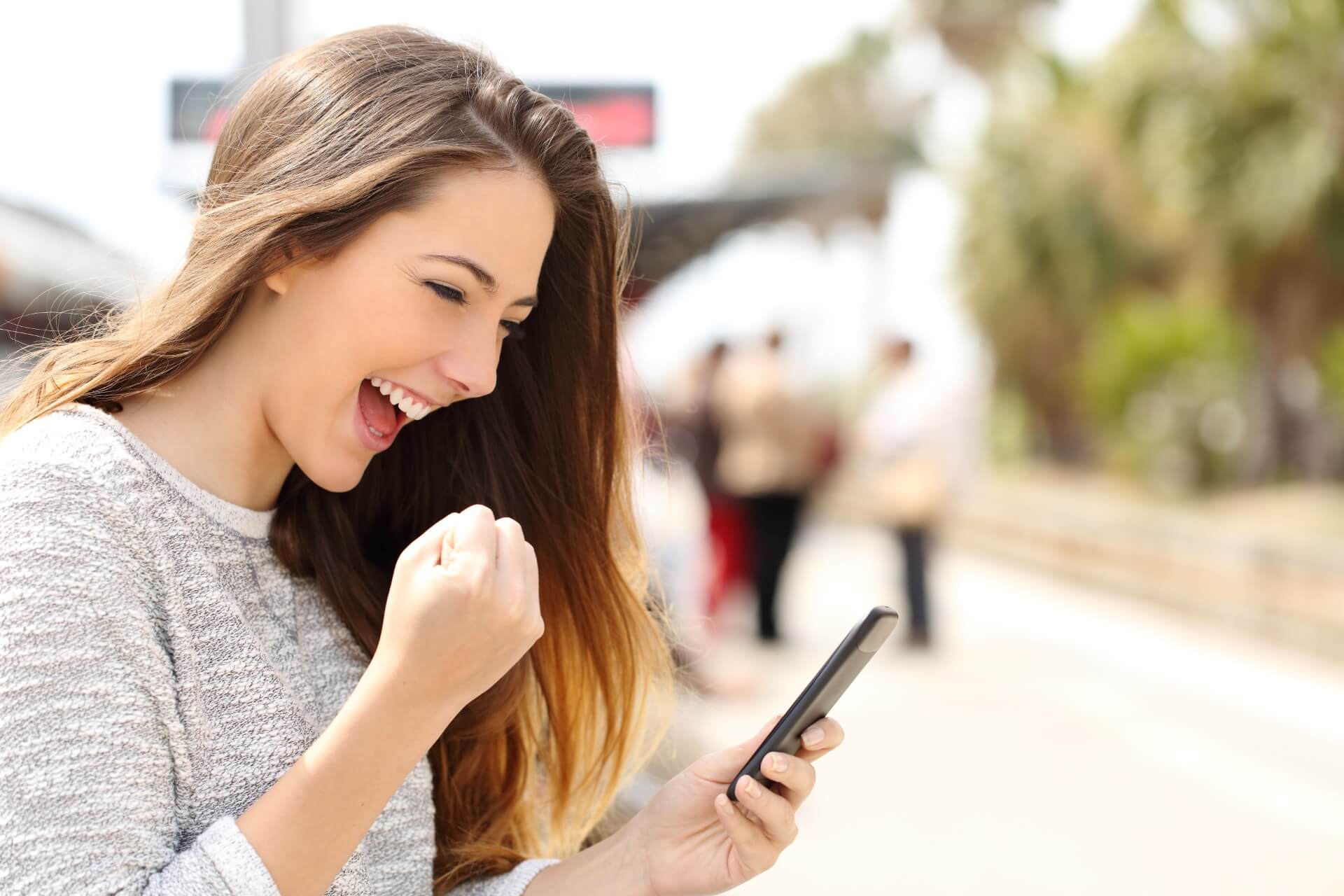 Euphoric woman watching her smartphone in a train station