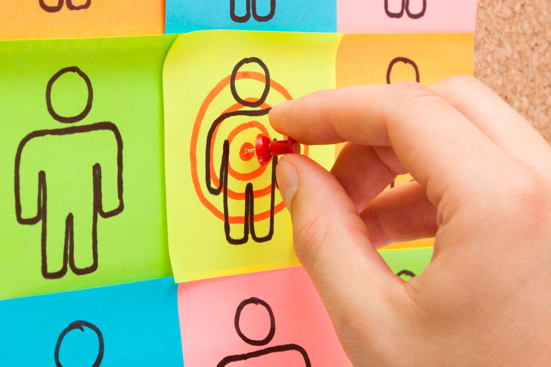 Hand pinning a post-it on a board